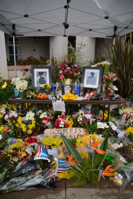 A display of flowers, photos and signs sits in front of the Santa Cruz Police Department in remembrance of two deceased officers. These were the first two officers to be killed in the line of duty in the city of Santa Cruz. Photo by Jessica Tran.